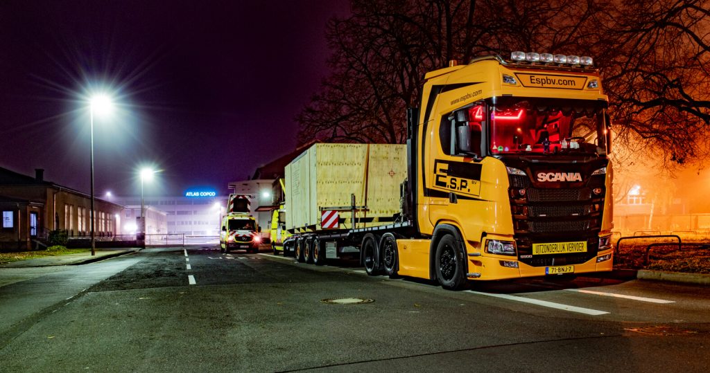 Gele vrachtwagen op nachtelijke weg. Grote lading.