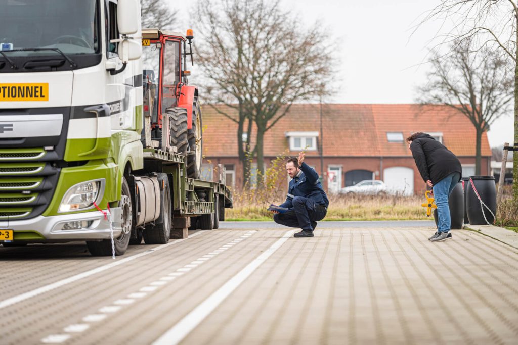 Tractor op vrachtwagen, man controleert lading.