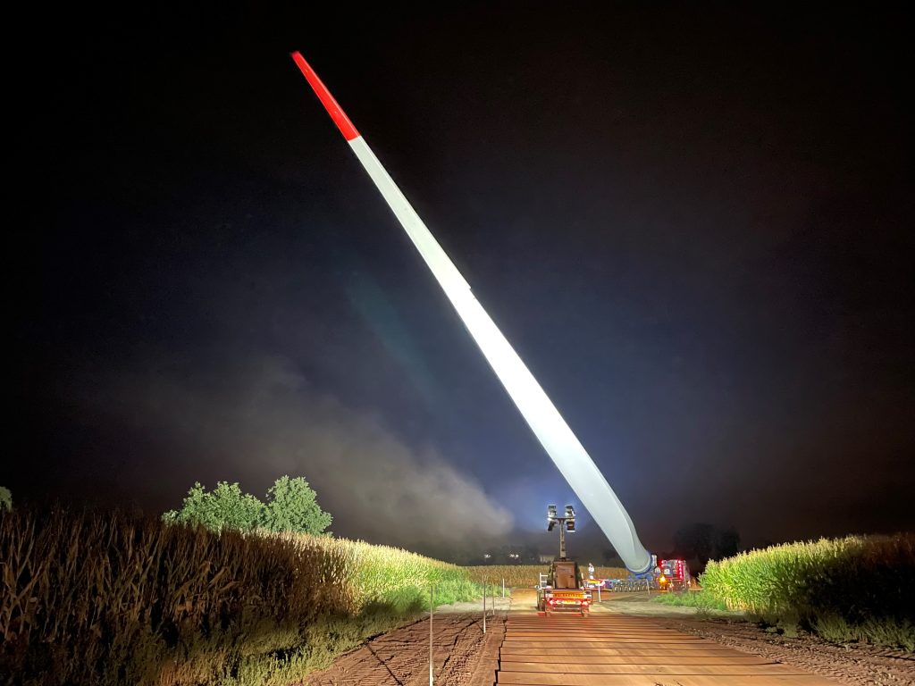 Nachttransport windturbineblad op vrachtwagen door veld
